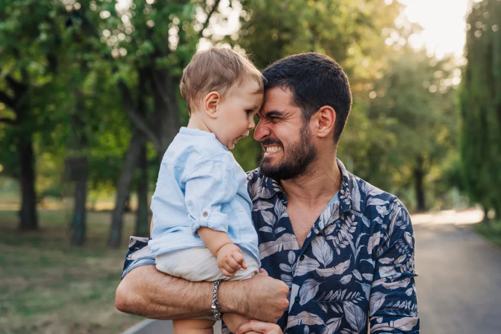 Tată și bebeluș față în față în parc, ședință foto familie în lumină naturală