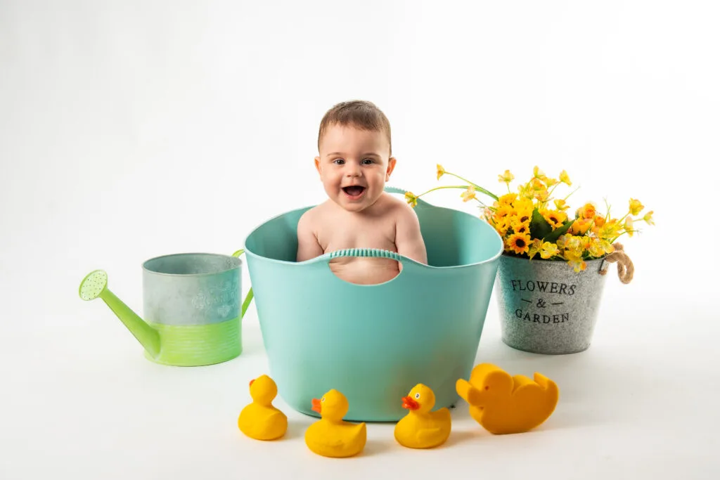 Bebeluș zâmbitor în lighean turcoaz cu rățuște galbene, ședință foto studio București
