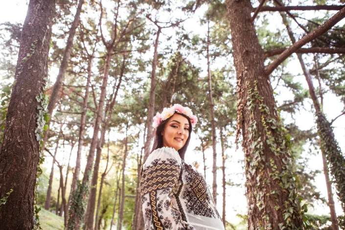Tânără în costum tradițional românesc și coronița florală, ședință foto în pădure