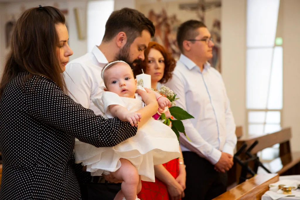 Bebeluș în rochie albă la botez, familie în biserică, fotografie emoționantă București