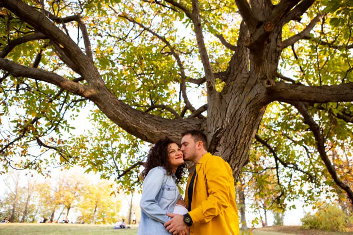 Cuplu în ședință foto romantică de toamnă sub copac maiestuos în parc