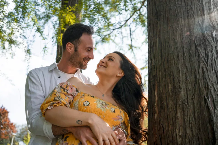 Cuplu îndrăgostit îmbrățișat lângă copac în parc, ședință foto romantică București