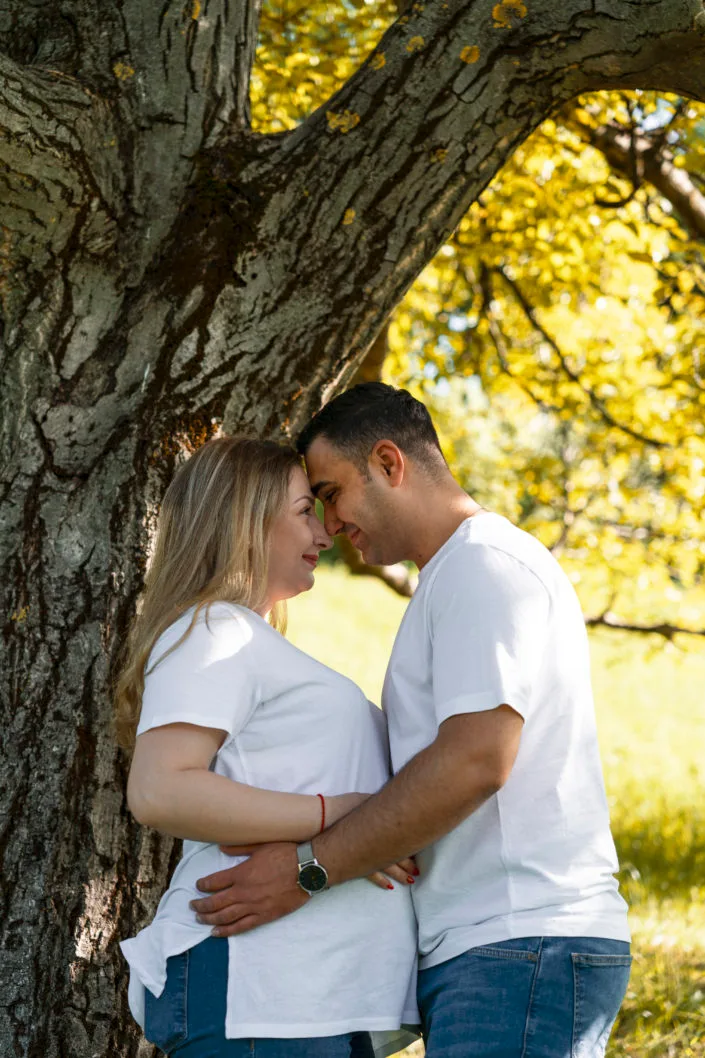 Cuplu în ședință foto romantică sub copac, lumină naturală caldă de vară