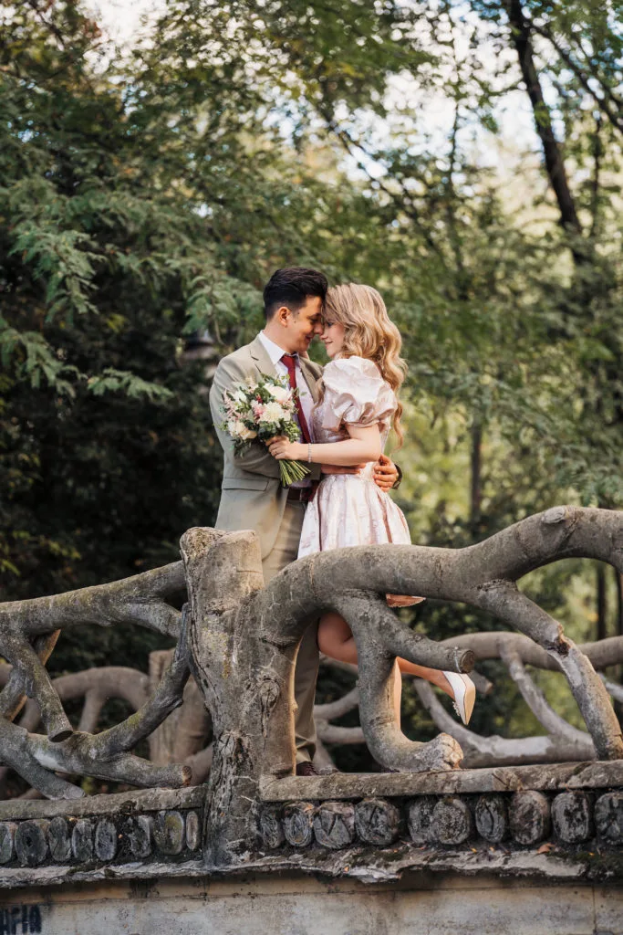 Cuplu de miri îmbrățișați pe pod rustic în parc, fotografie de nuntă romantică București