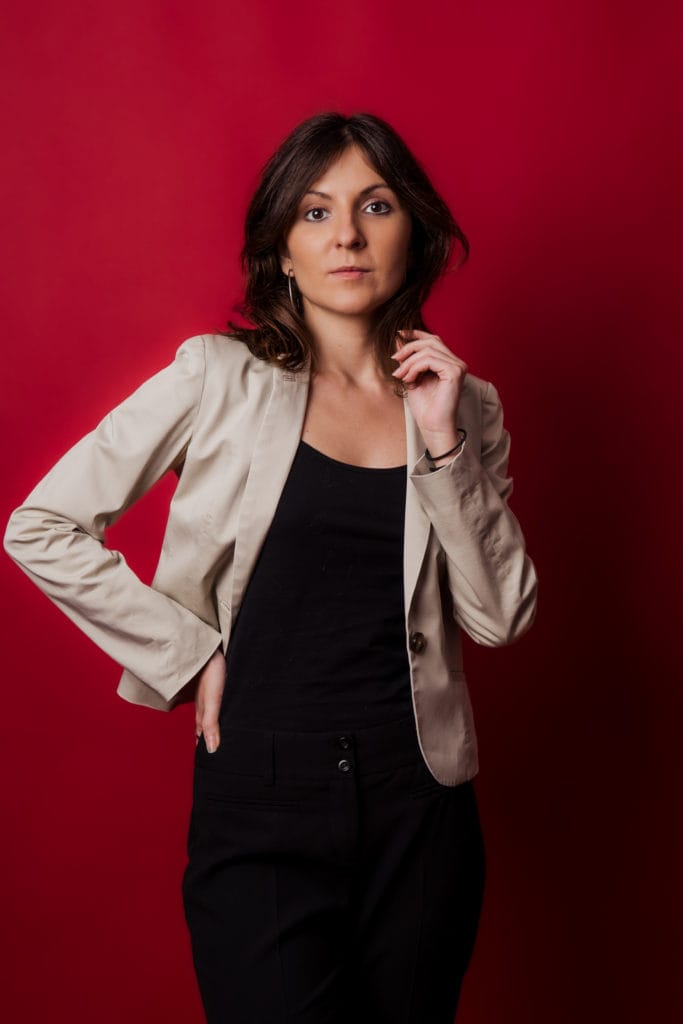 Ședință foto portret femeie în studio cu fundal roșu și sacou bej