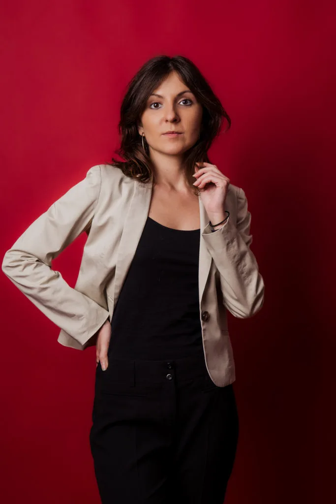 Ședință foto portret femeie în studio cu fundal roșu și sacou bej