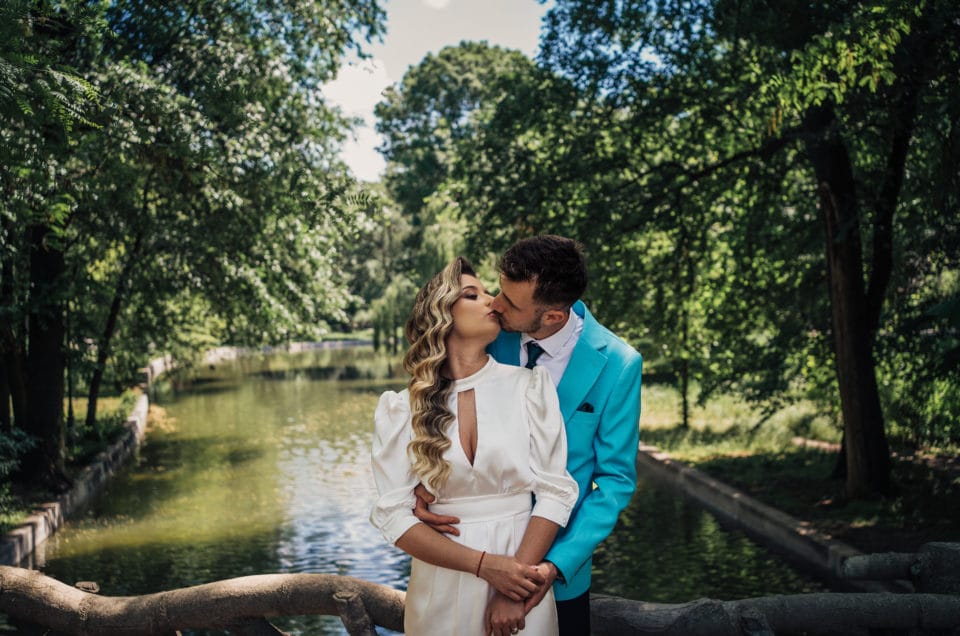 Cuplu de miri sărutându-se lângă lac în parc, fotografie de nuntă București