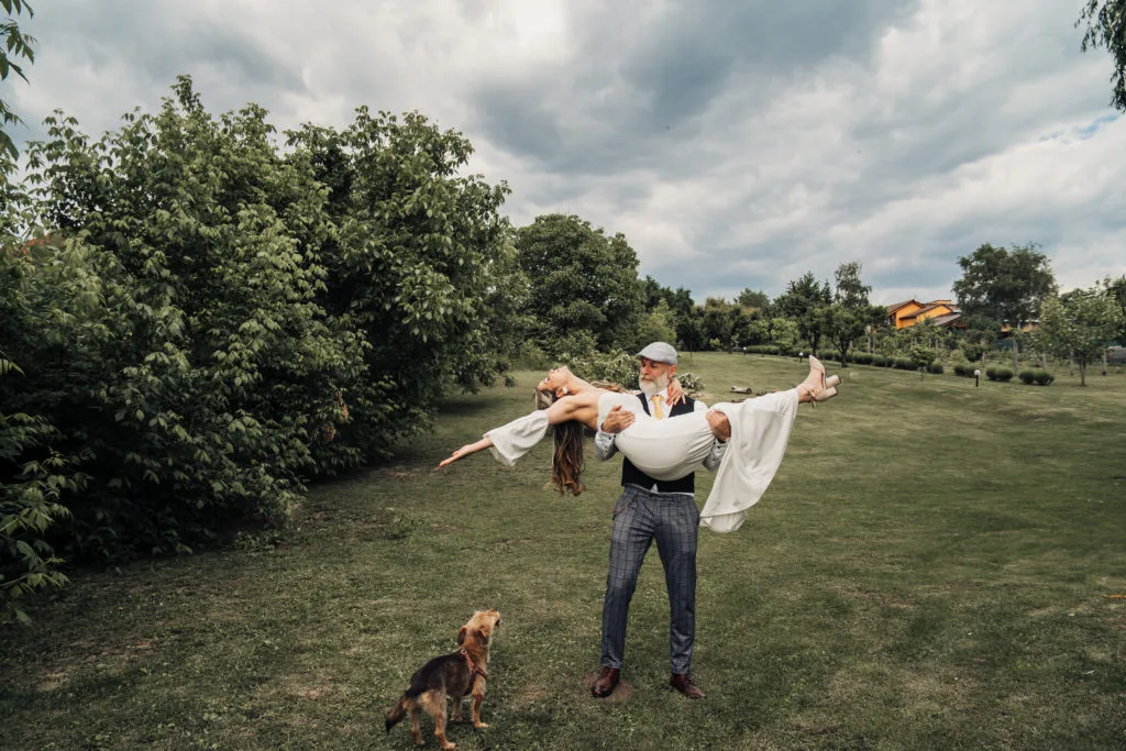 Mire ridicând mireasa în aer în grădină, fotografie de nuntă naturală