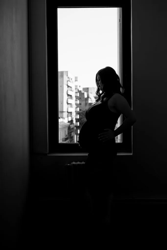 Siluetă maternitate la fereastră în alb-negru, ședință foto gravidă București