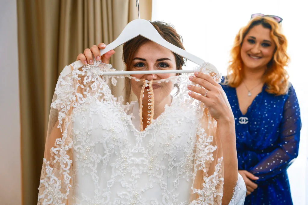 Mireasă fericită ținând rochia de nuntă cu dantelă, fotografie emoționantă București