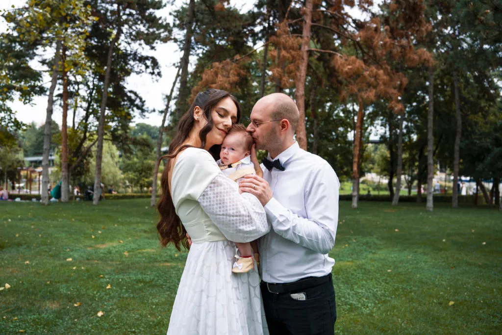 Fotografie de botez, familie fericită cu bebeluș în parc, lumină naturală București