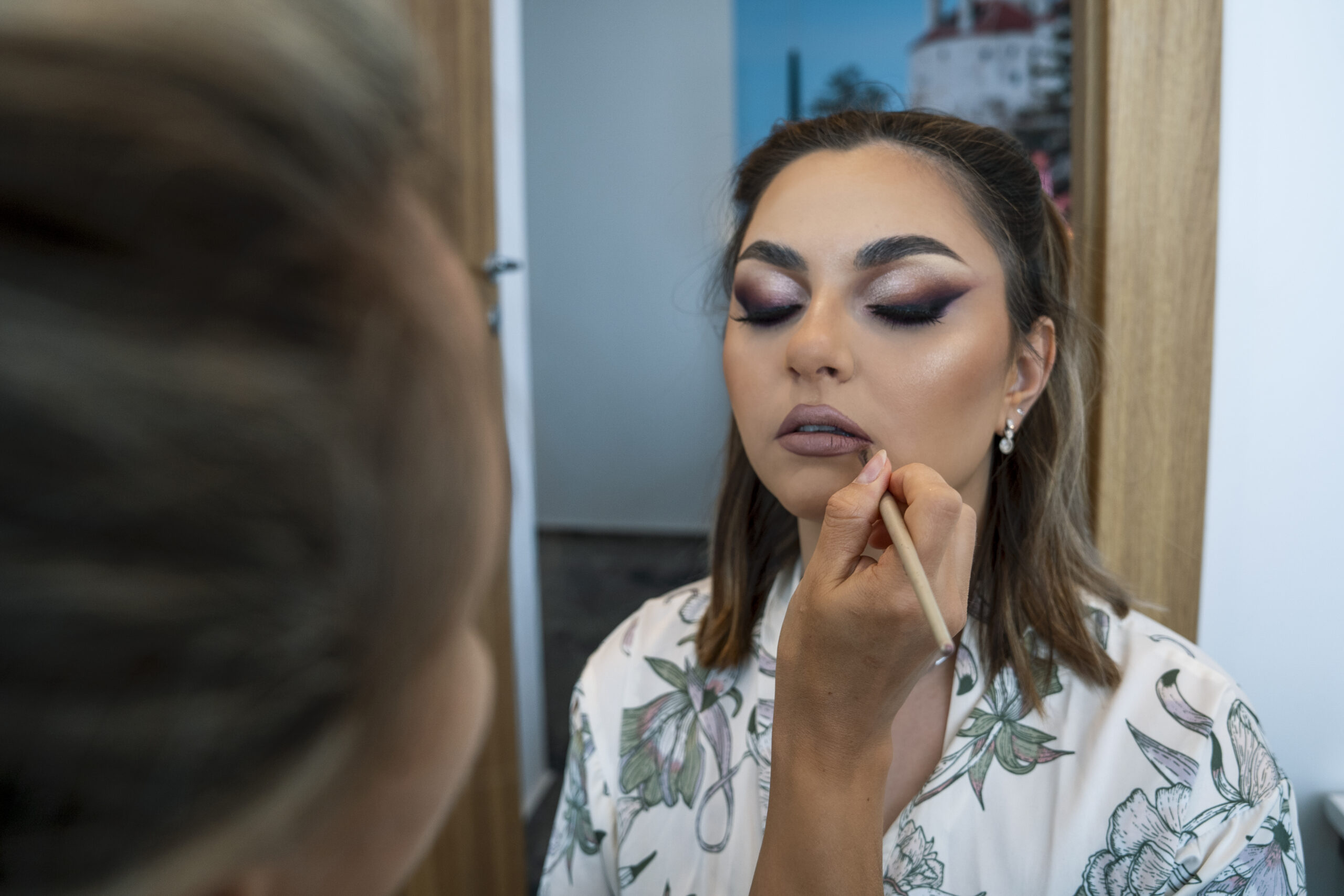 Makeup artist aplicând ruj pe buzele unei mirese elegante, ședință foto București