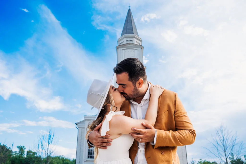 Miri sărutându-se în fața bisericii, fotografie de nuntă romantică în aer liber