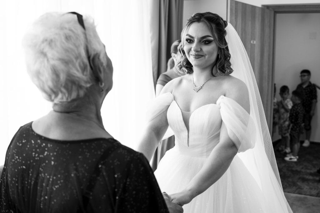 Mireasă în rochie albă ținând mâinile cu mama, fotografie de nuntă emoționantă București