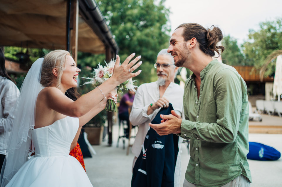 Mireasă râzând cu un invitat la nuntă în aer liber, fotografie de nuntă București