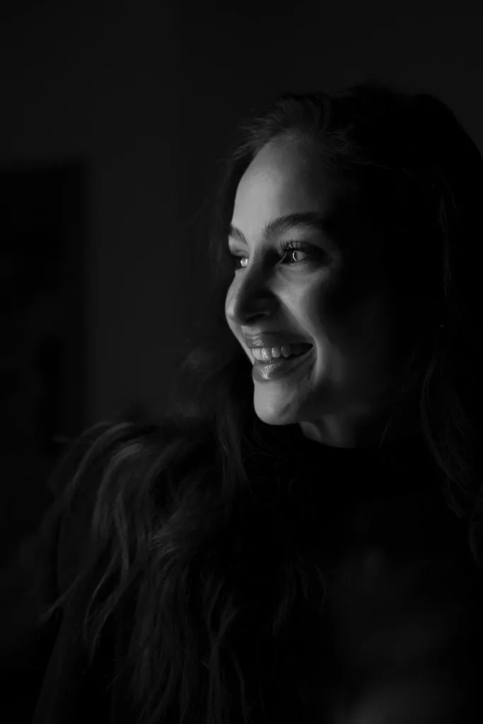 Portret artistic în alb-negru, femeie zâmbind, lumină dramatică, ședință foto profesională București