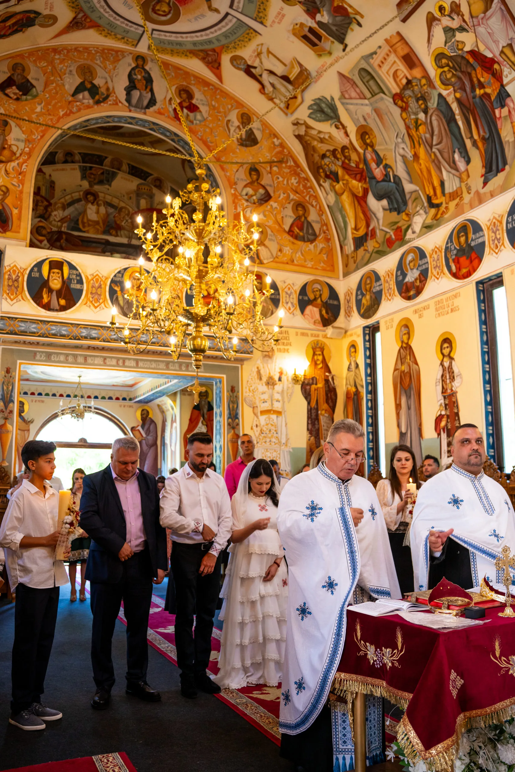 Preot și copil la botez în biserică ortodoxă cu fresce, fotografie emoționantă București