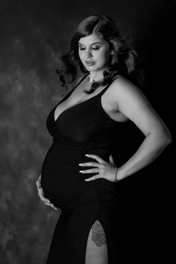 Femeie însărcinată în rochie neagră elegantă, ședință foto maternitate București alb-negru