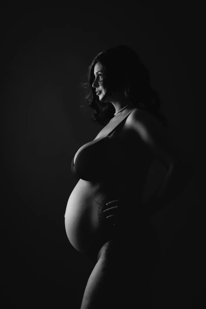 Femeie însărcinată în profil, ședință foto maternitate, lumină dramatică alb-negru București