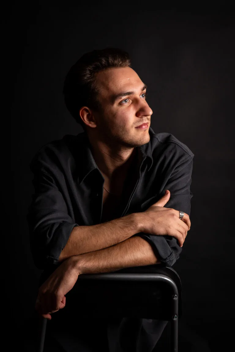 Tânăr bărbat în ședință foto portret studio, lumină dramatică pe fond negru