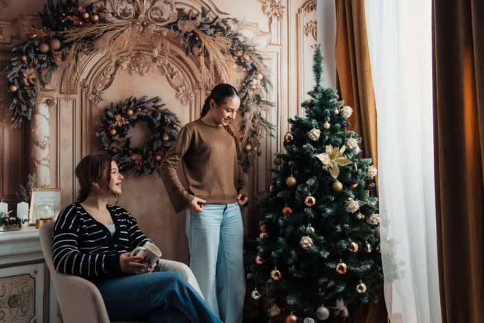 Ședință foto familie de Crăciun în interior elegant cu brad decorat și coronițe