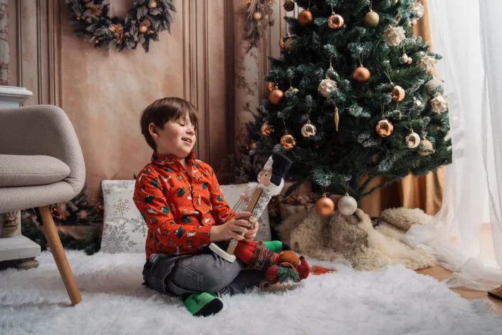 Băiat fericit cu jucărie de Crăciun, ședință foto copii în decor festiv