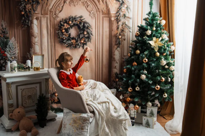 Fetiță în rochie roșie cu ornament de Crăciun, ședință foto tematică de iarnă