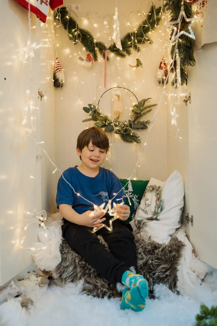 Băiat fericit la ședință foto de Crăciun cu steluță luminoasă și decorațiuni festive
