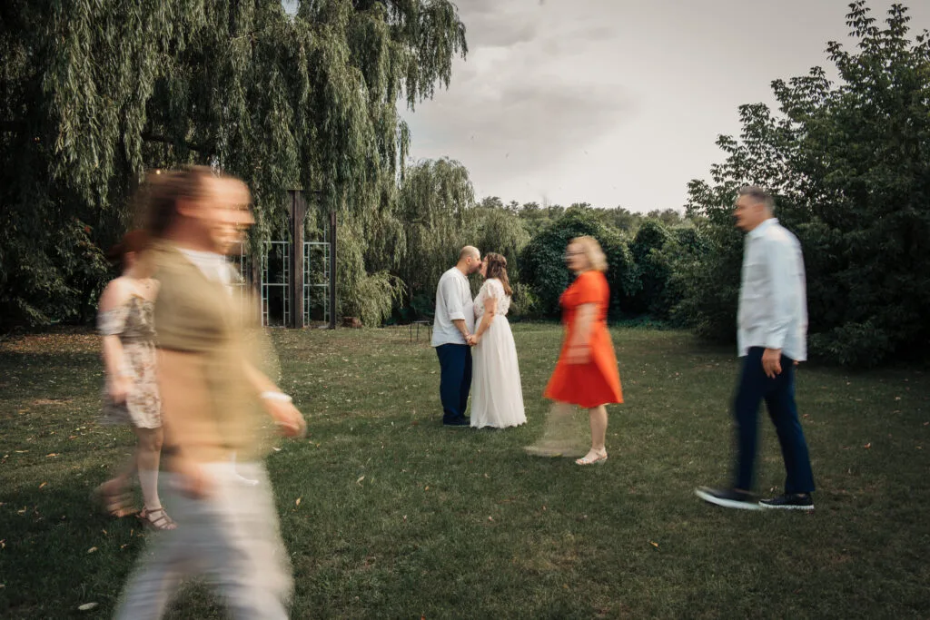 Miri sărutându-se în parc, fotografie artistică de nuntă București cu invitați în mișcare