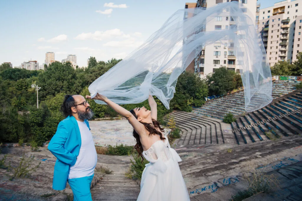 Mireasă aruncând vălul în aer lângă mire, fotografie creativă de nuntă București