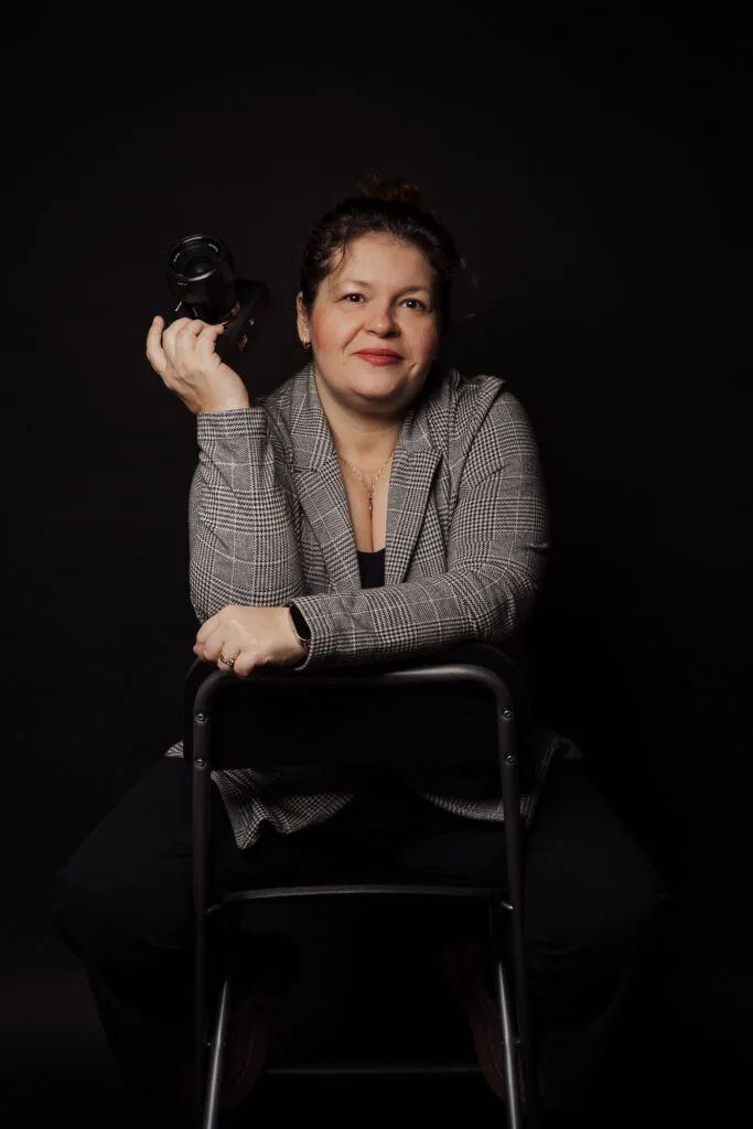 Cătălina Urse fotograf profesionist București ținând aparat foto în studio, portret elegant