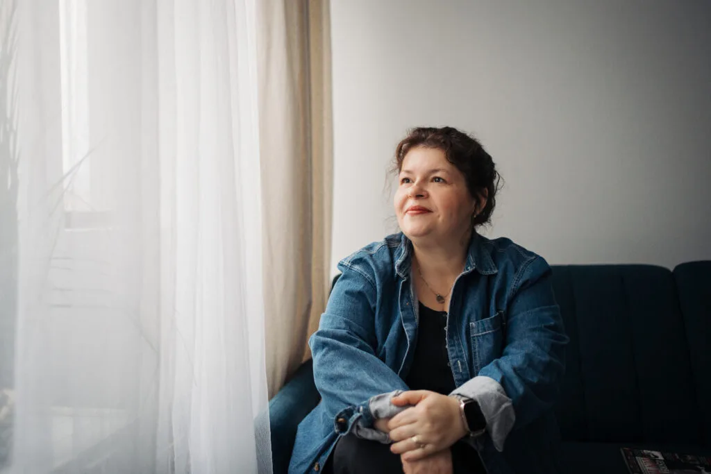 Femeie relaxată pe canapea privind gânditor, portret natural în lumină difuză București